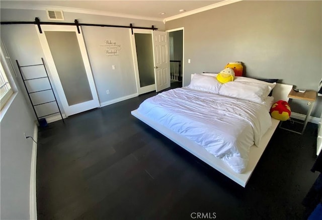 bedroom featuring ornamental molding, a barn door, visible vents, and baseboards