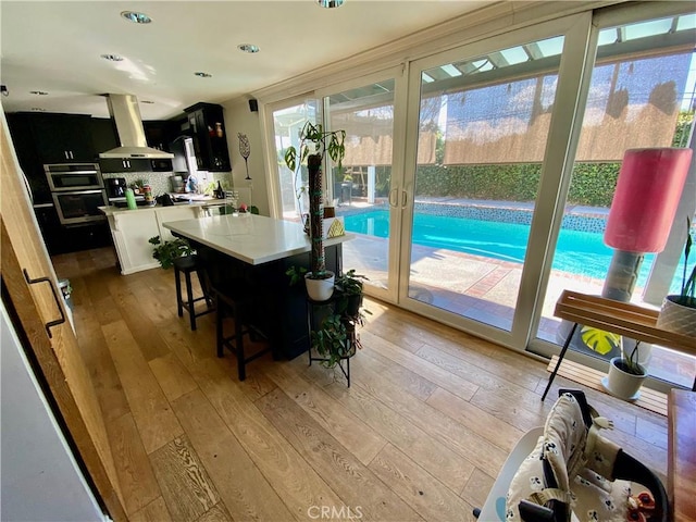 interior space with dark cabinetry, a kitchen island, oven, a kitchen breakfast bar, and extractor fan