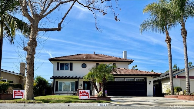 mediterranean / spanish house featuring an attached garage, a tile roof, concrete driveway, and stucco siding