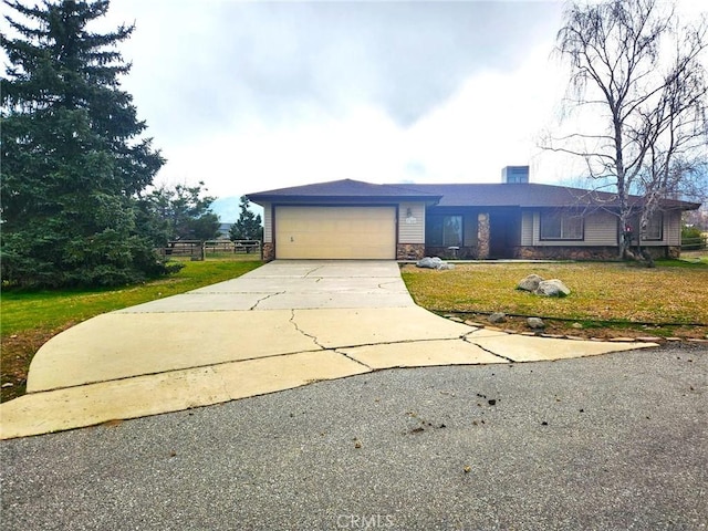 view of front of home featuring a chimney, an attached garage, a front yard, stone siding, and driveway