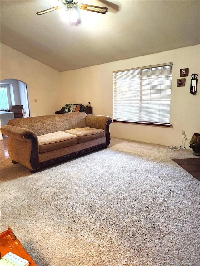 carpeted living room with ceiling fan and arched walkways