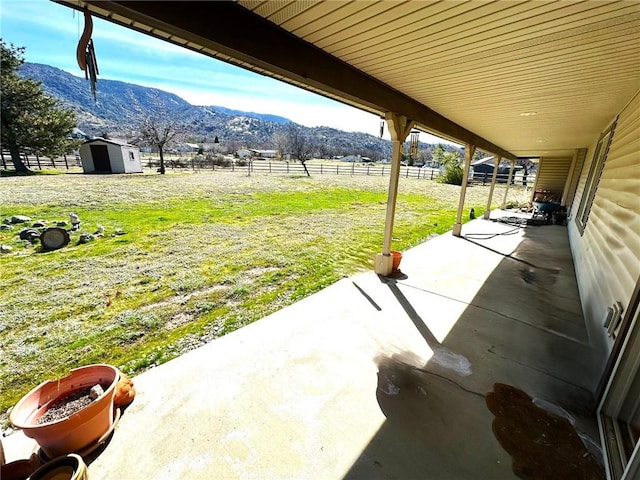 view of patio with a storage shed, a rural view, a mountain view, and an outbuilding