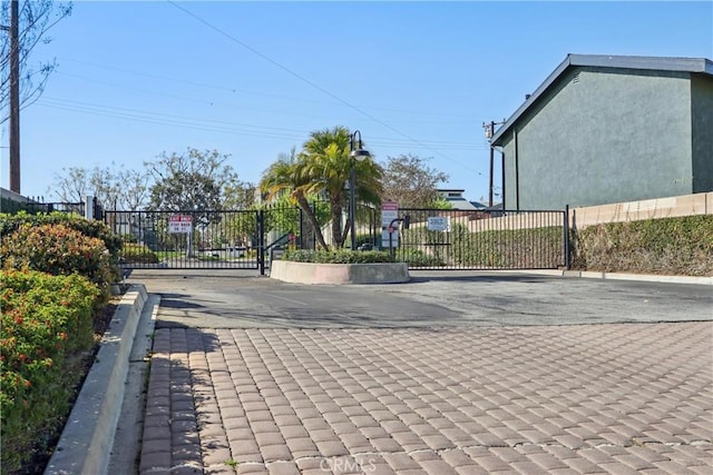 view of road featuring a gated entry, curbs, and a gate