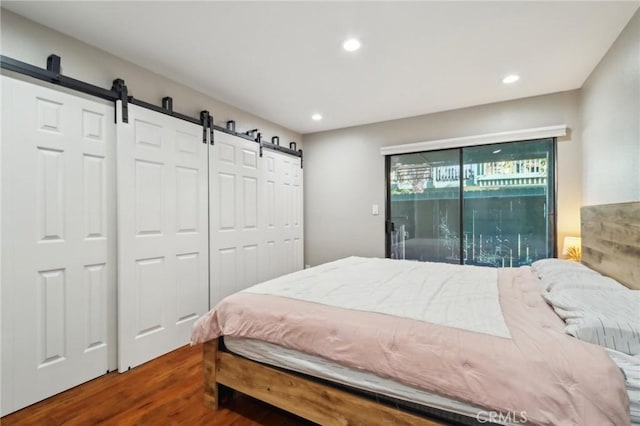 bedroom with access to exterior, a barn door, recessed lighting, and wood finished floors