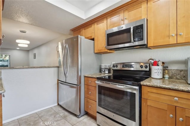 kitchen featuring light tile patterned flooring, appliances with stainless steel finishes, brown cabinetry, and light stone countertops