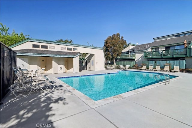 community pool with a patio and fence