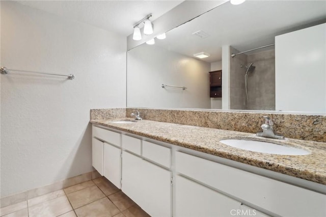 full bathroom featuring a sink, tiled shower, double vanity, and tile patterned floors