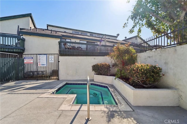 view of pool with fence and a hot tub