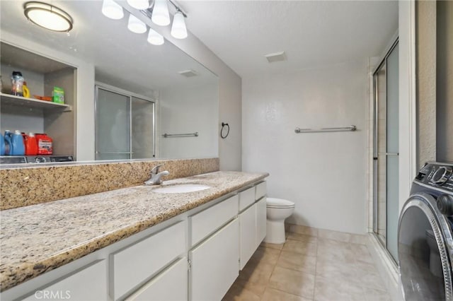 bathroom with tile patterned flooring, a stall shower, washer / clothes dryer, and vanity