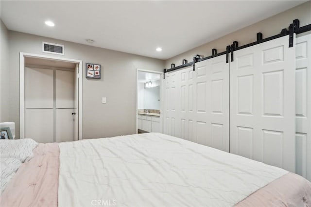 bedroom with recessed lighting, a barn door, visible vents, and ensuite bath