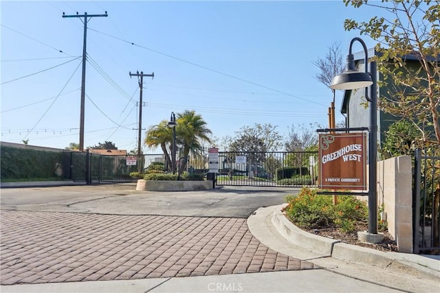 view of road featuring curbs, a gated entry, street lighting, and a gate