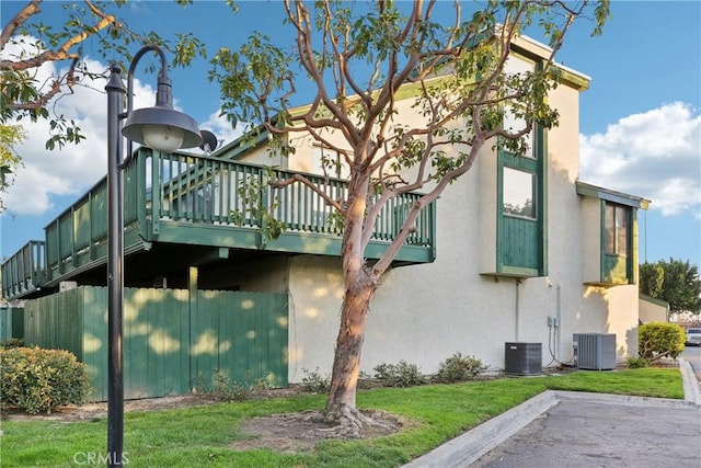 view of property exterior featuring central air condition unit, a lawn, and stucco siding