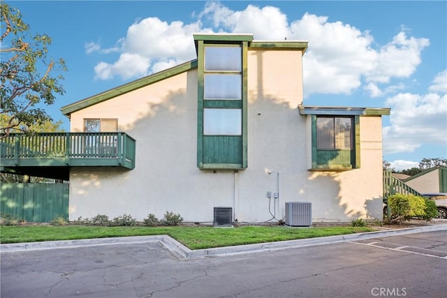 view of home's exterior with stucco siding, central AC unit, and fence