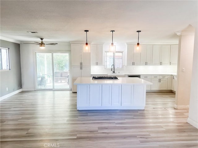 kitchen featuring a center island, a wealth of natural light, light countertops, hanging light fixtures, and white cabinets