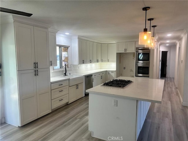 kitchen with a center island, stainless steel appliances, light countertops, white cabinets, and a sink