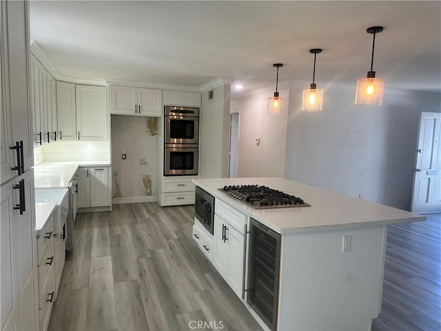 kitchen featuring beverage cooler, white cabinets, a kitchen island, appliances with stainless steel finishes, and light countertops