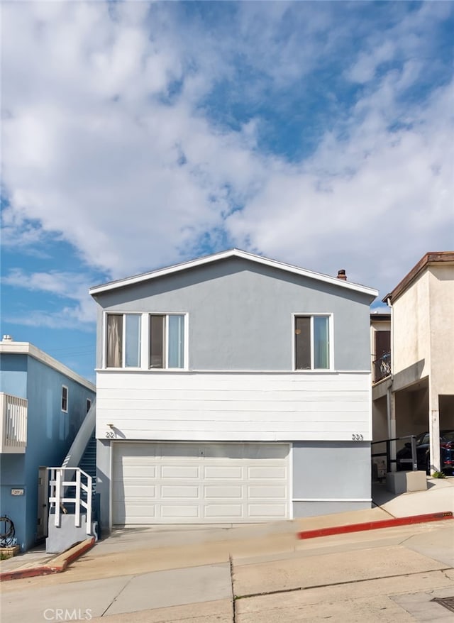 view of front facade with a garage, driveway, and stucco siding