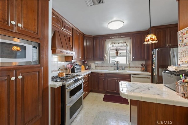 kitchen featuring tile countertops, stainless steel appliances, visible vents, a sink, and premium range hood