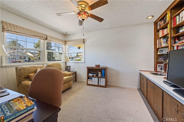 office featuring light carpet, a textured ceiling, a sink, and a ceiling fan