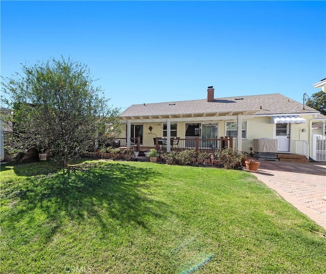 back of property with a lawn, a chimney, and stucco siding