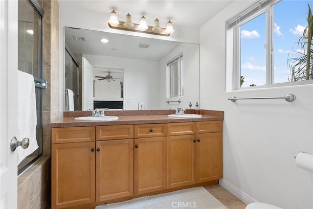 full bath with double vanity, tiled shower, a sink, and visible vents