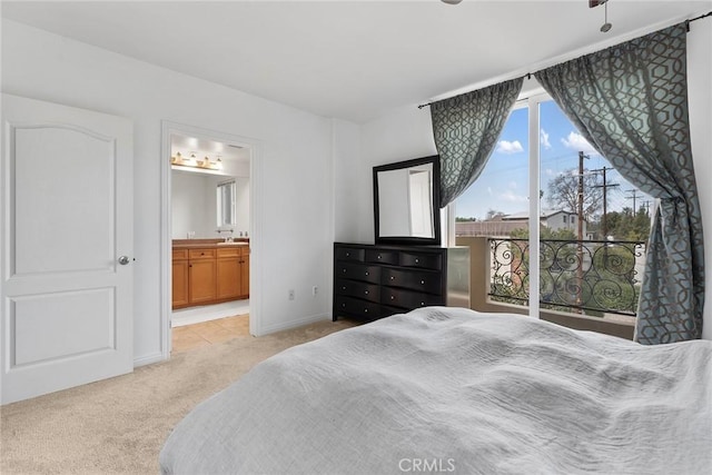 bedroom featuring ensuite bathroom, baseboards, and light colored carpet