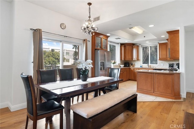 dining space with a healthy amount of sunlight, light wood-type flooring, and a raised ceiling