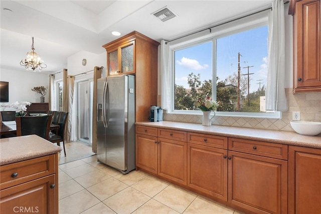 kitchen with brown cabinets, visible vents, stainless steel refrigerator with ice dispenser, and light countertops