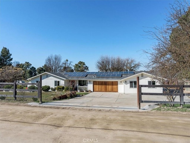 view of front facade featuring roof mounted solar panels, fence, and concrete driveway