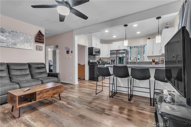 living area featuring ceiling fan, recessed lighting, wood finished floors, visible vents, and baseboards