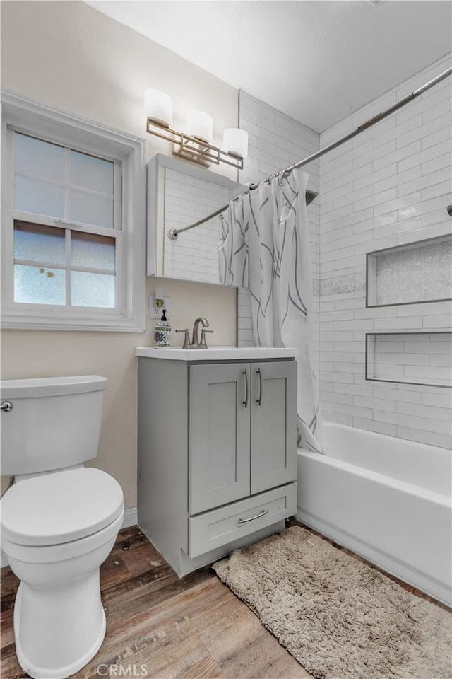 bathroom with shower / bathtub combination with curtain, toilet, vanity, wood finished floors, and baseboards