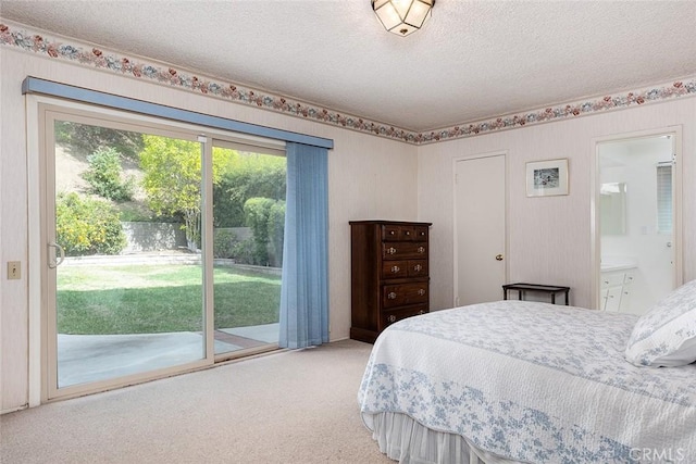 carpeted bedroom with access to exterior, connected bathroom, and a textured ceiling