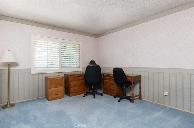 home office with a wainscoted wall, light carpet, a textured ceiling, and wallpapered walls