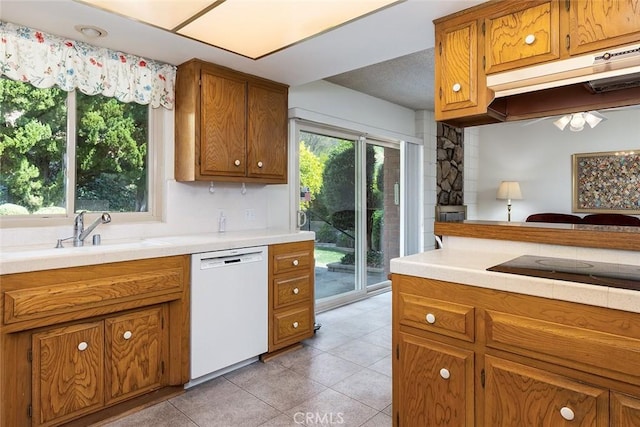 kitchen featuring brown cabinetry, white dishwasher, light countertops, and a sink