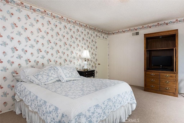 carpeted bedroom featuring wallpapered walls, visible vents, and a textured ceiling