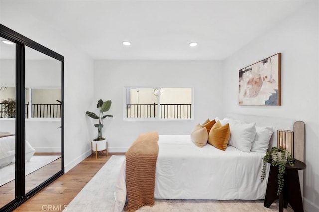 bedroom featuring baseboards, multiple windows, wood finished floors, and recessed lighting