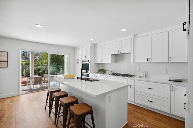 kitchen featuring light wood-style floors, a kitchen bar, a sink, and oven