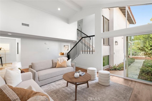 living area featuring visible vents, stairway, wood finished floors, high vaulted ceiling, and beam ceiling