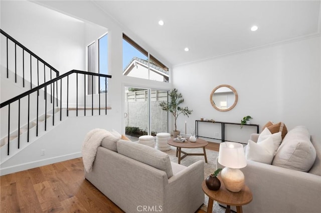 living area with stairs, baseboards, crown molding, and wood finished floors