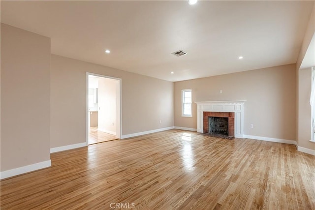 unfurnished living room featuring baseboards, visible vents, and light wood finished floors