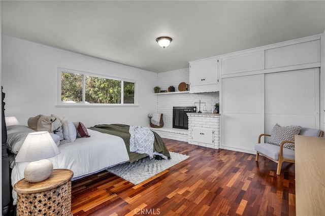 bedroom with a closet, a fireplace, and dark wood-type flooring