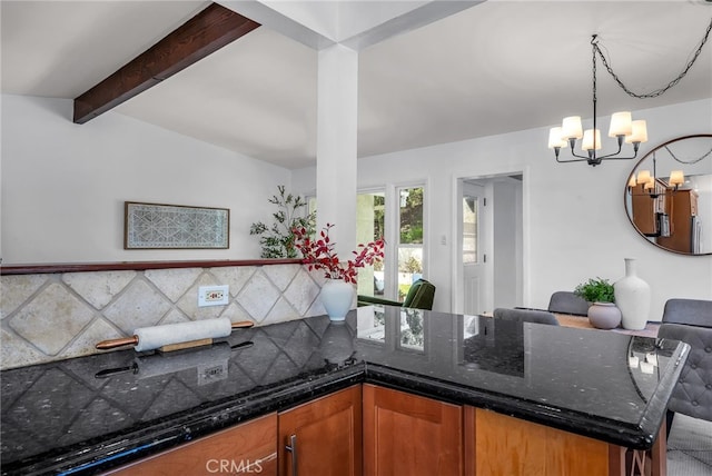 kitchen featuring brown cabinetry, hanging light fixtures, vaulted ceiling with beams, a peninsula, and an inviting chandelier