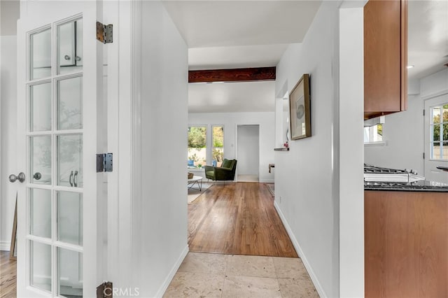 corridor featuring baseboards and beam ceiling