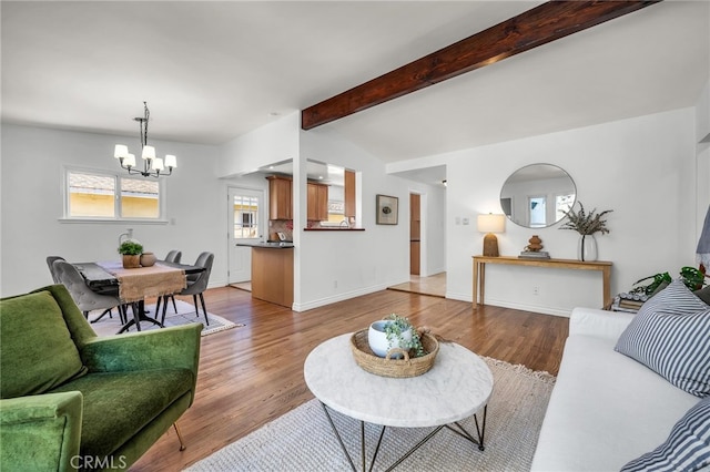 living room featuring baseboards, a notable chandelier, beamed ceiling, and light wood finished floors