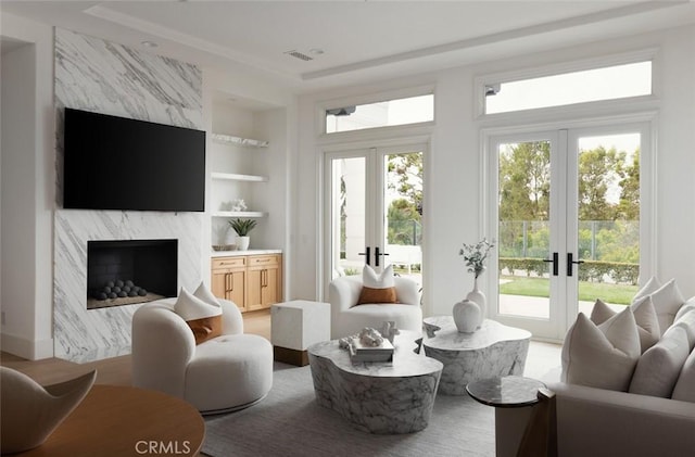 living room with built in features, a high end fireplace, french doors, and visible vents