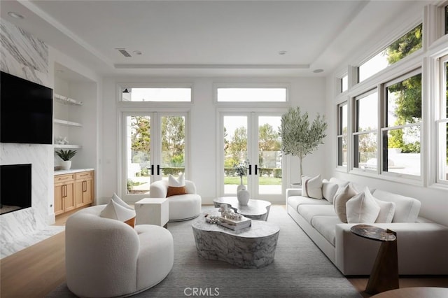 sunroom featuring a healthy amount of sunlight, a fireplace, visible vents, and french doors