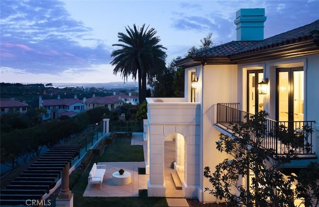 view of property exterior featuring a patio, fence, a balcony, and stucco siding