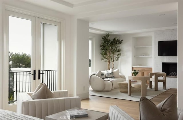 living room featuring built in shelves, a fireplace, and wood finished floors