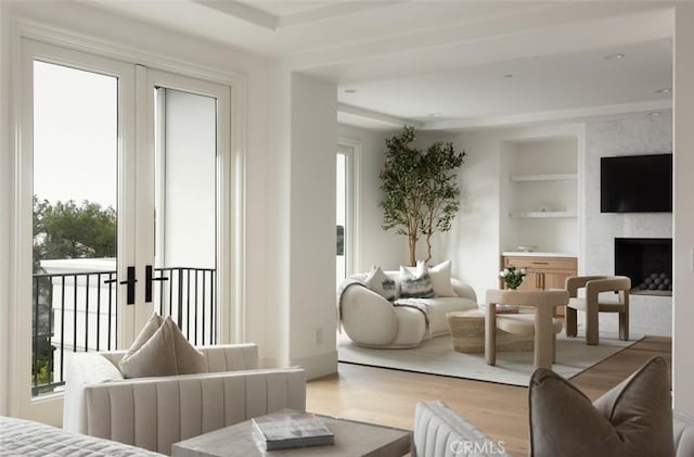 living room with a fireplace, built in features, french doors, and wood finished floors