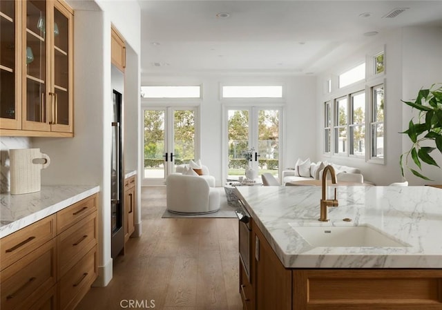 kitchen featuring a sink, open floor plan, french doors, brown cabinets, and hardwood / wood-style floors